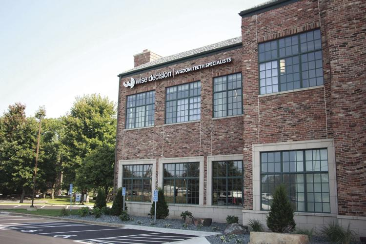 Brick building with large windows and trees around it.