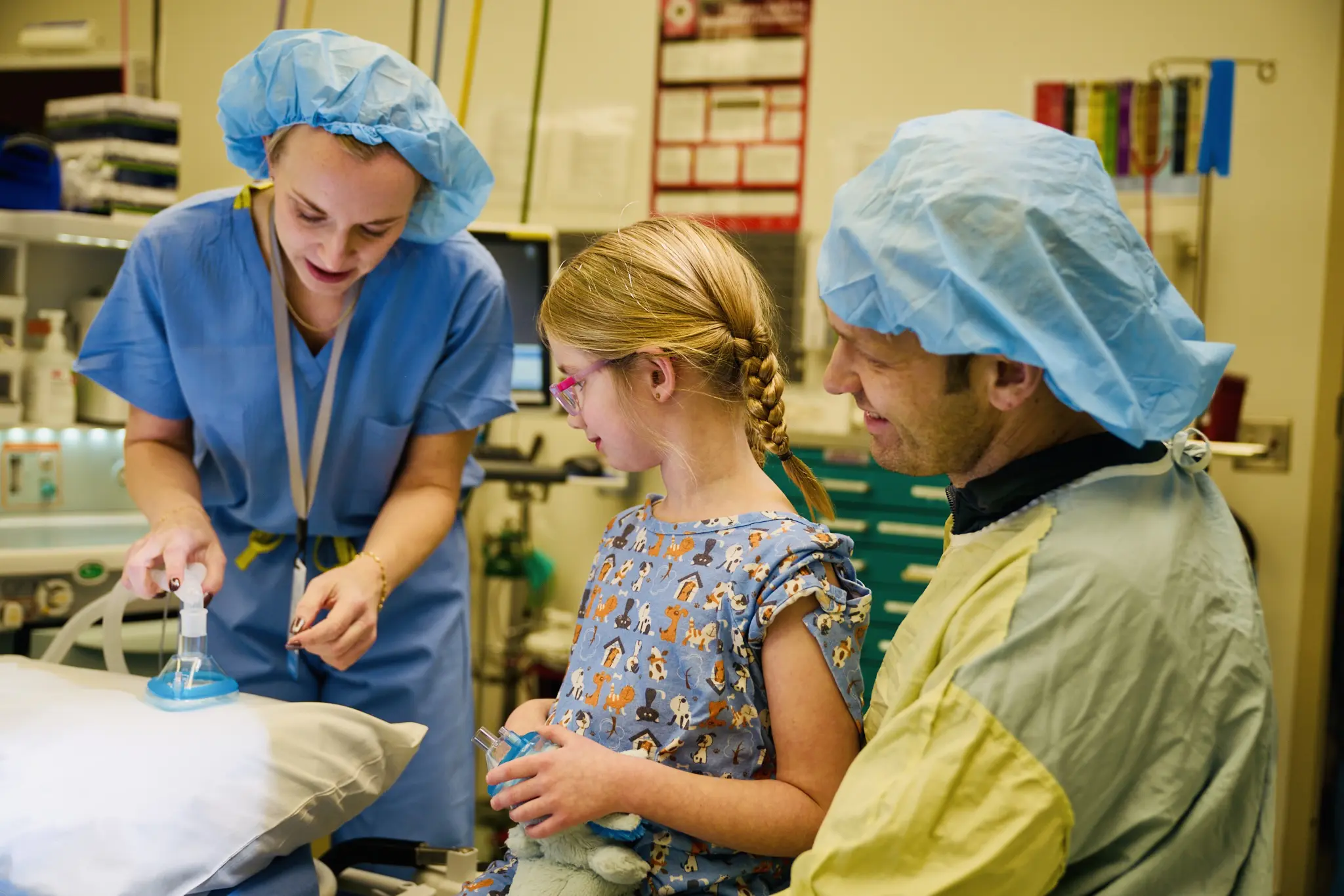 Child wearing surgical cap with medical staff in operating room.