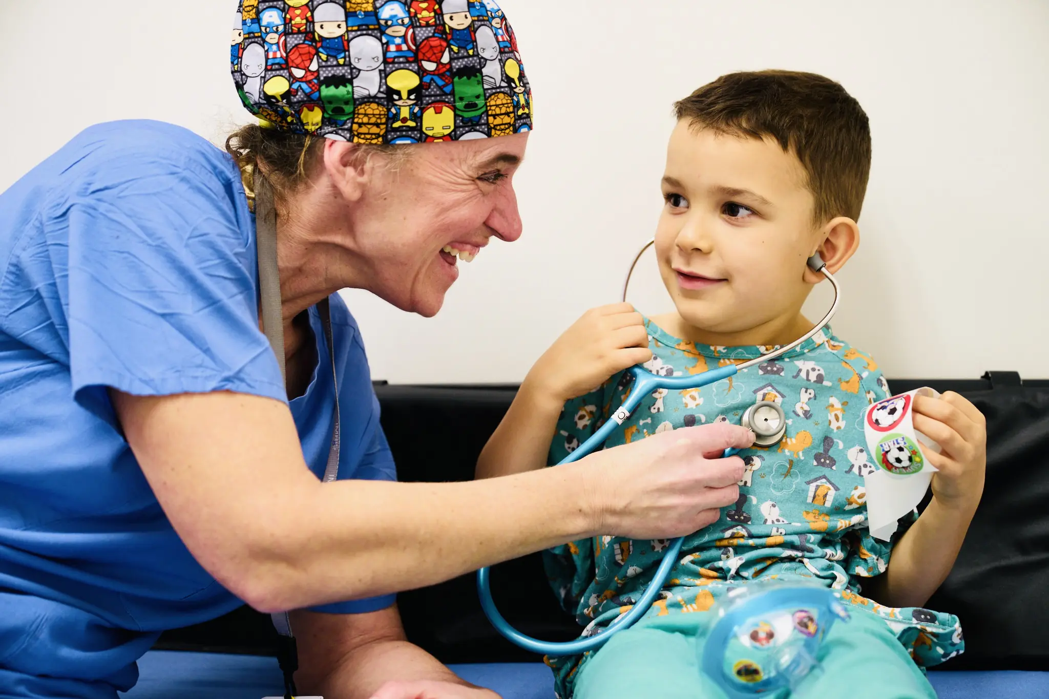 A cheerful pediatrician listens to a young boy's heartbeat with a stethoscope.