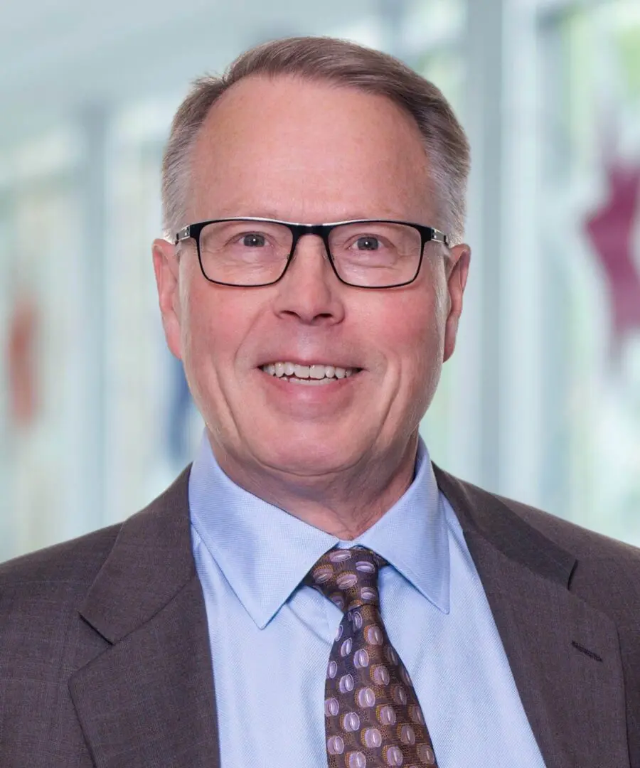 Portrait of a middle-aged man wearing glasses and a suit.