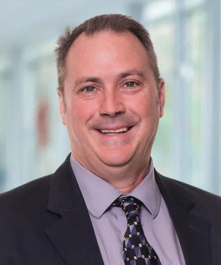 Smiling man in a suit with a patterned tie.
