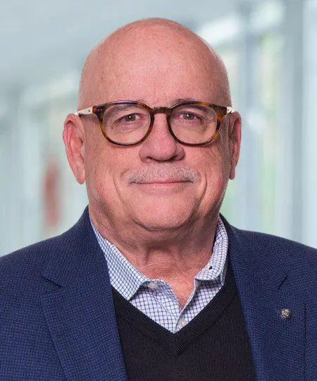 Portrait of an elderly man wearing glasses and a suit jacket.