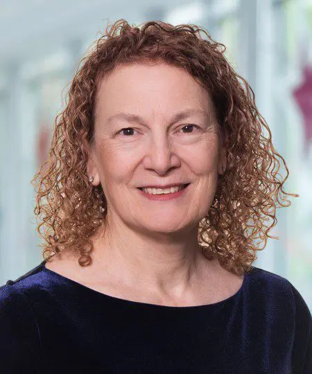 A smiling woman with curly hair in a professional setting.