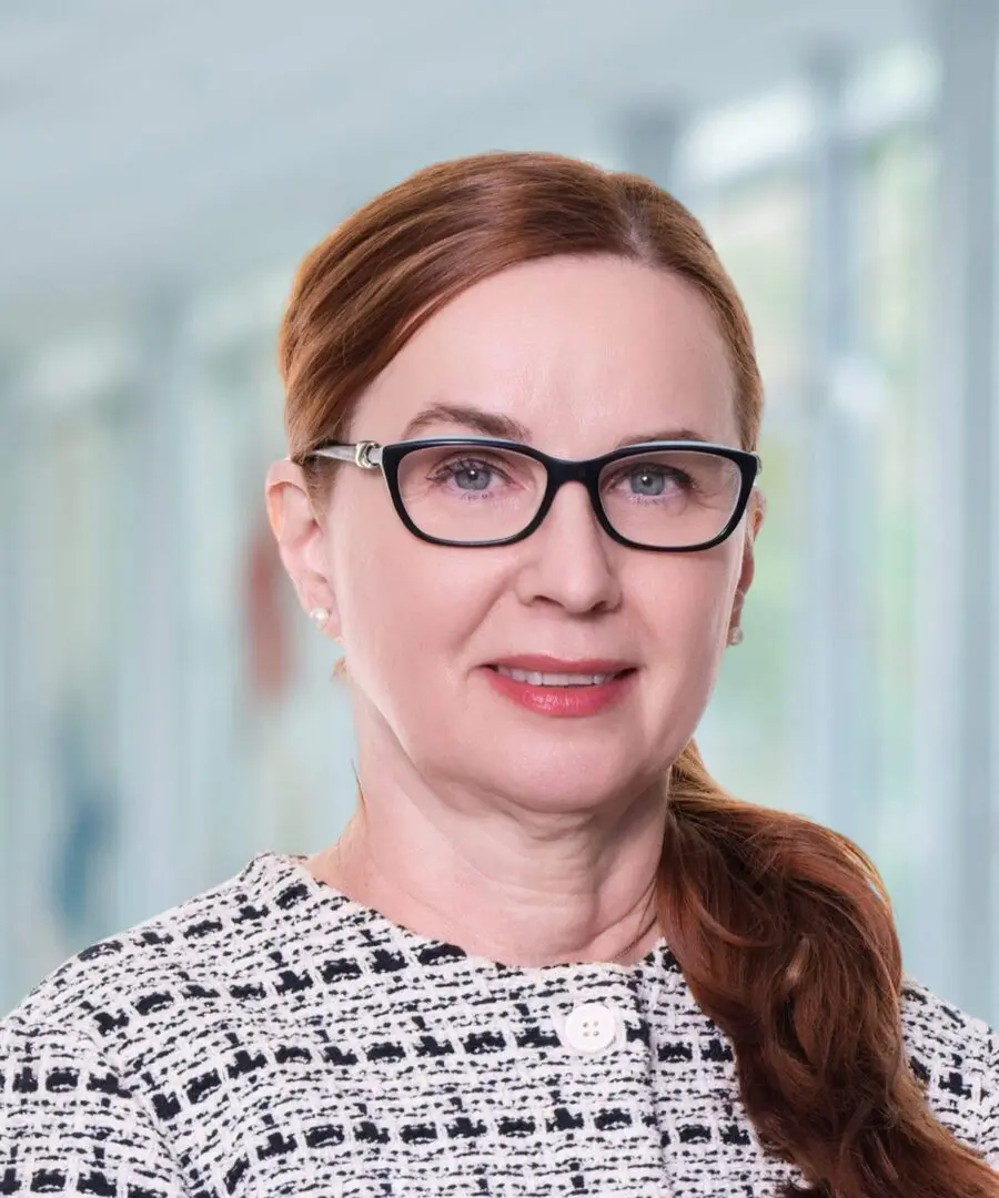 Woman with glasses and brown hair smiling.