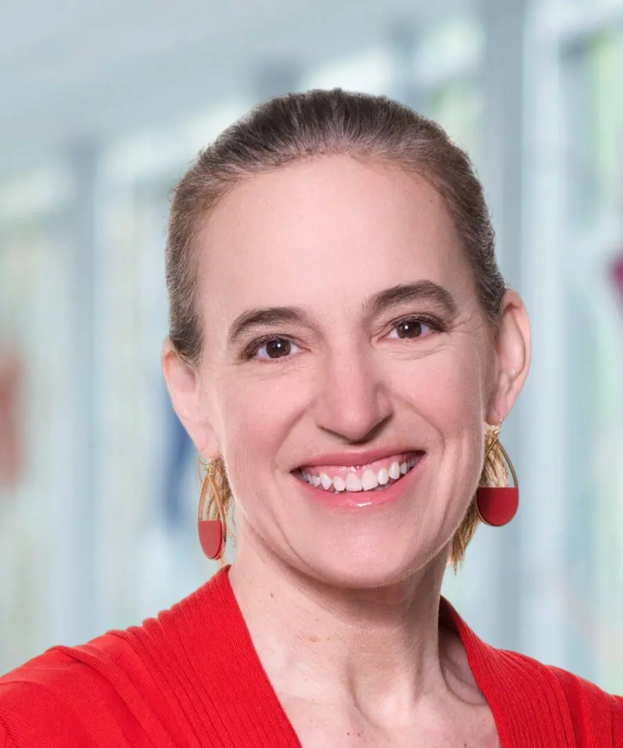 Smiling woman with earrings and red sweater.