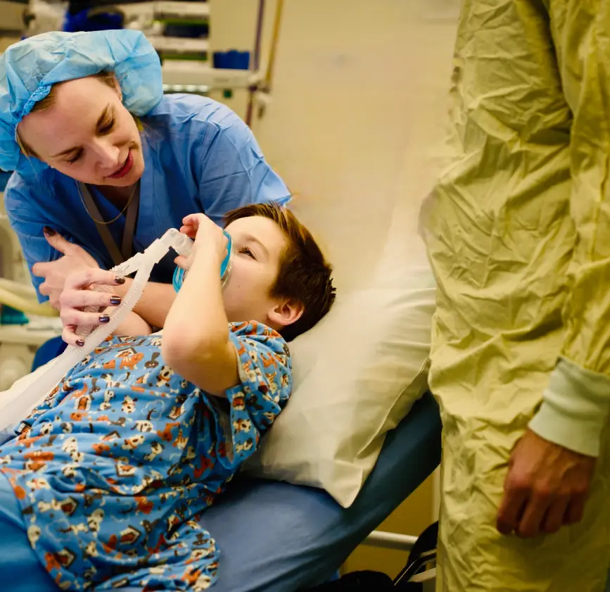 Nurse comforting a young child in a hospital bed.